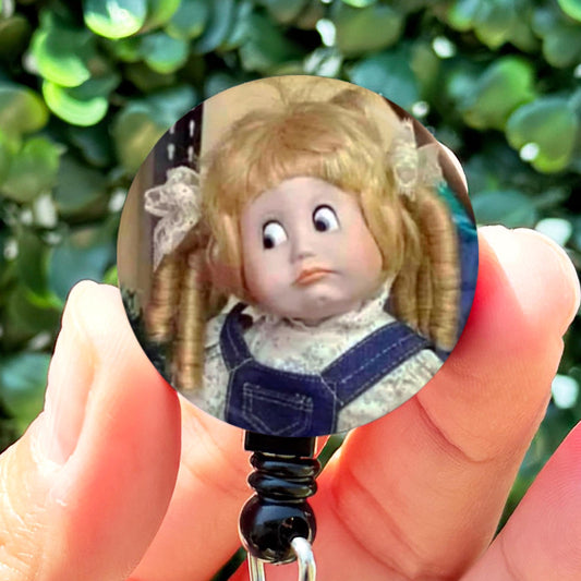 a person holding a keychain with a picture of a doll on it