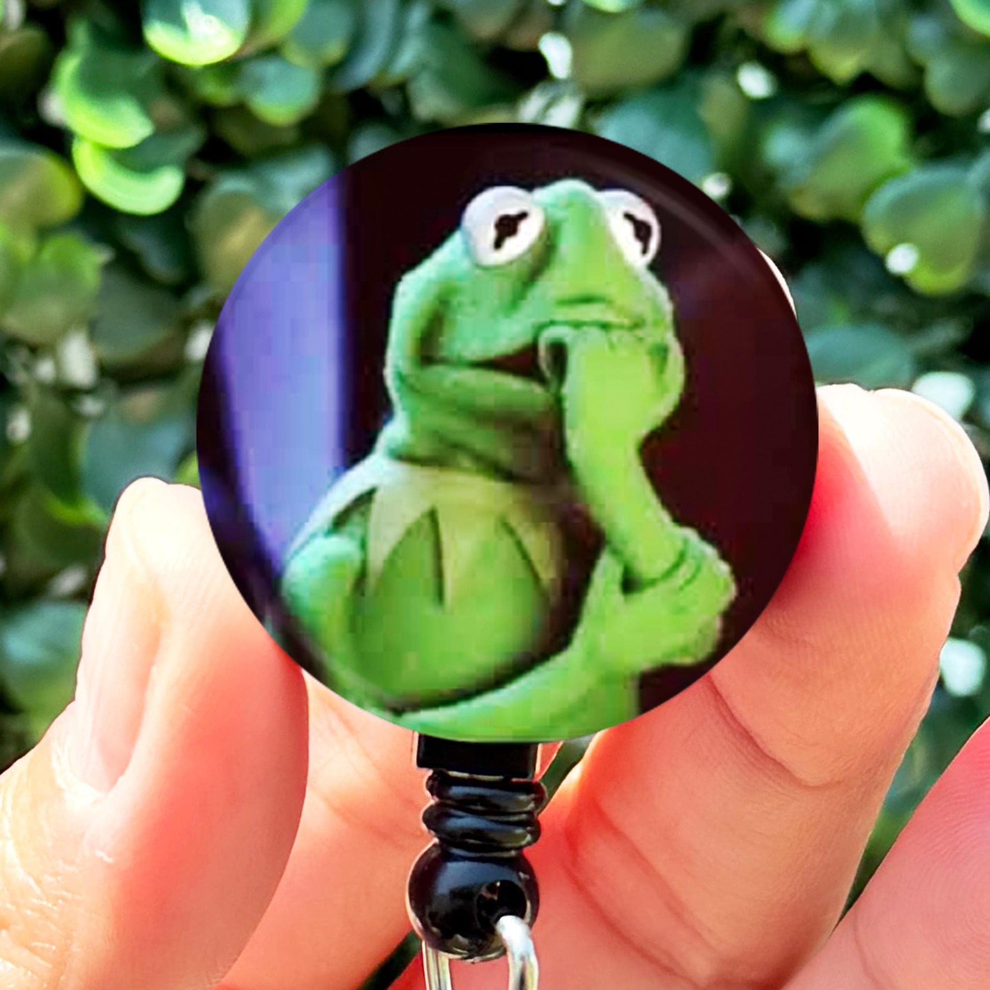 a person holding a badge with a picture of a frog on it