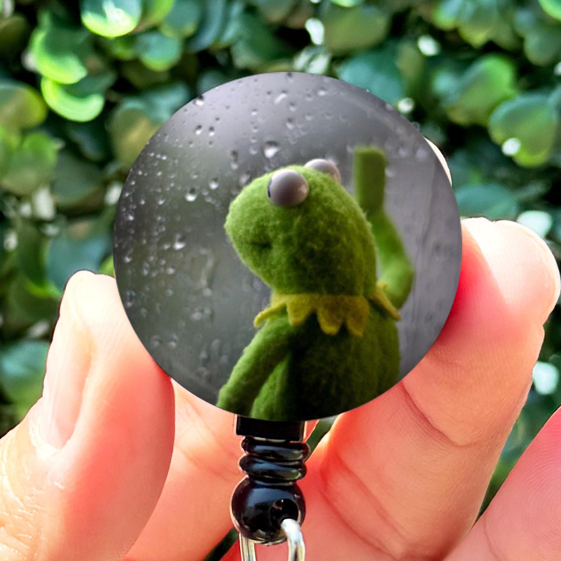 a person holding a key chain with a picture of a frog on it