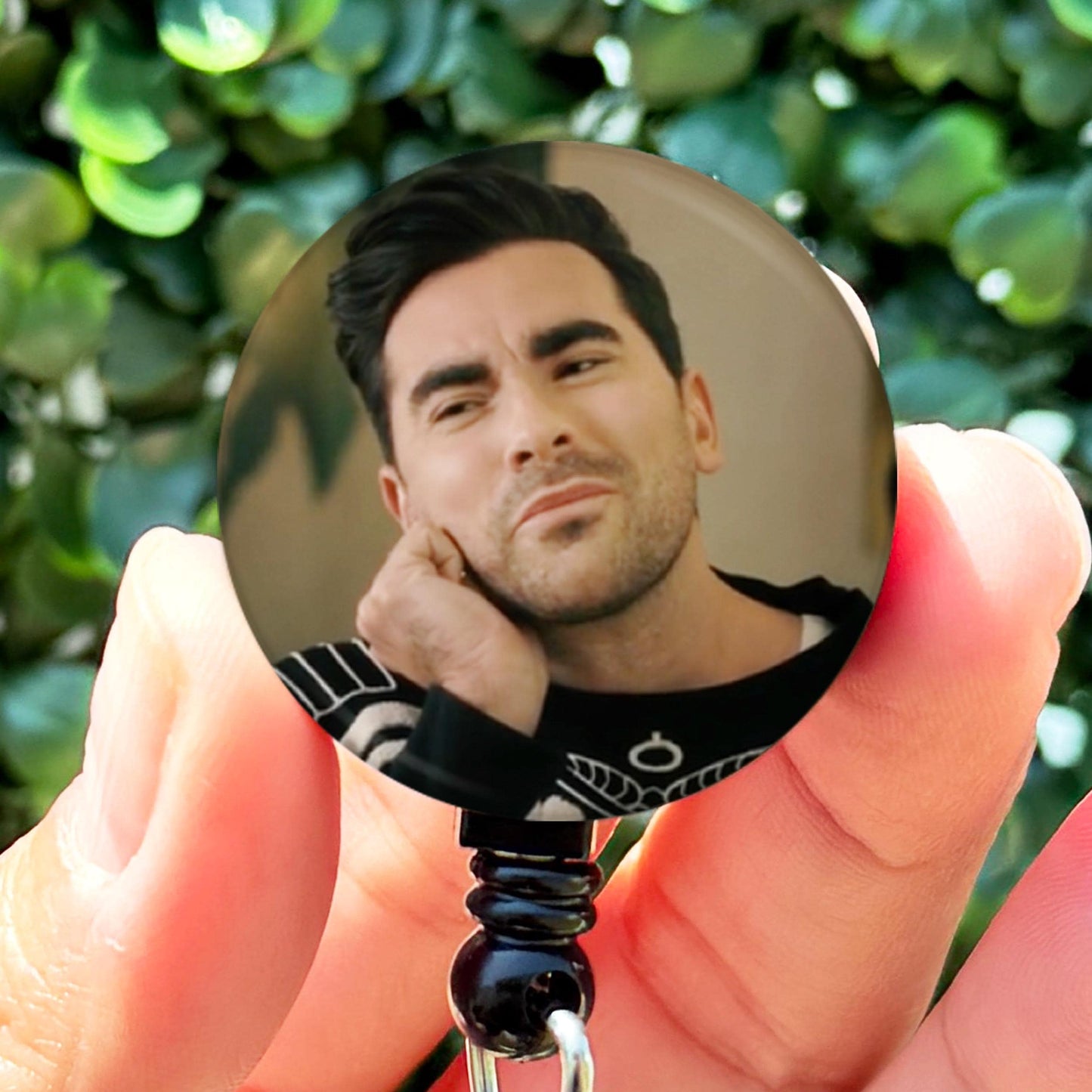 a person holding a badge with a picture of a man on it