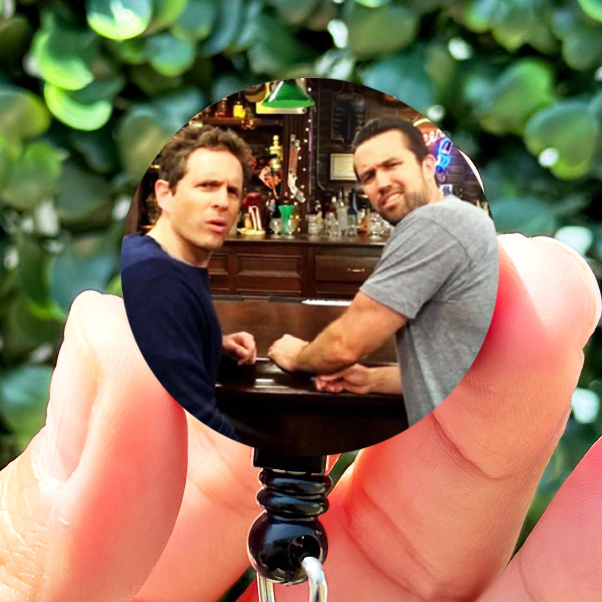 a person holding a small bottle opener with a picture of two men on it